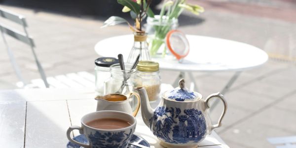 Tea set with blue floral patterns on a white table in bright daylight.