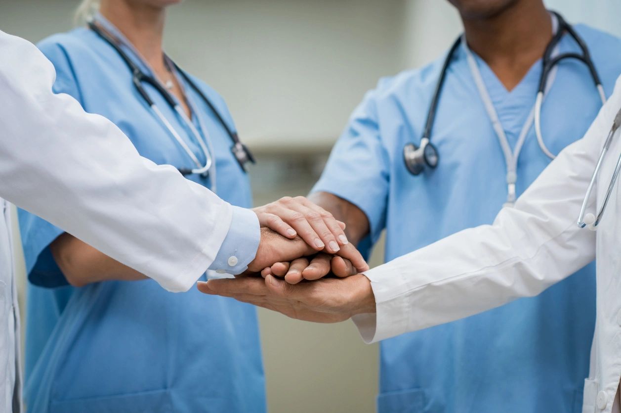 medical practitioners with hands on top of one another