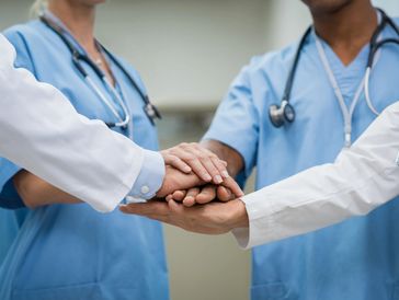 Healthcare professionals joining hands in teamwork and support.