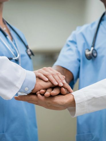 Healthcare professionals joining hands to show unity and support.
