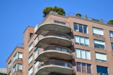 Curved balconies on a brick apartment building against clear sky.