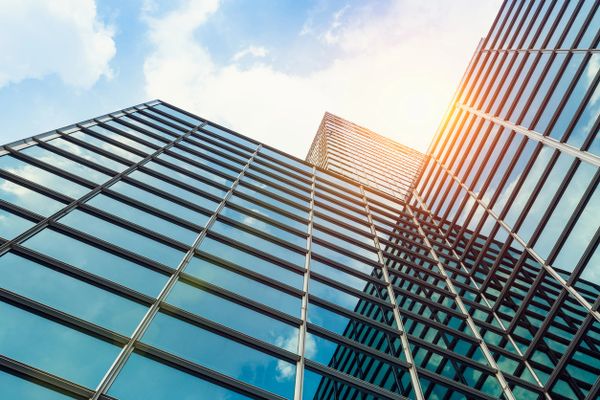 Modern glass skyscrapers reflecting the sky and sunlight.