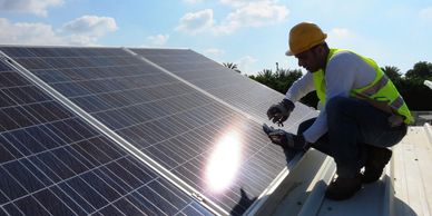 Worker installing solar panels on a rooftop under sunny skies.