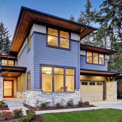 Modern two-story house with blue siding and stone accents.