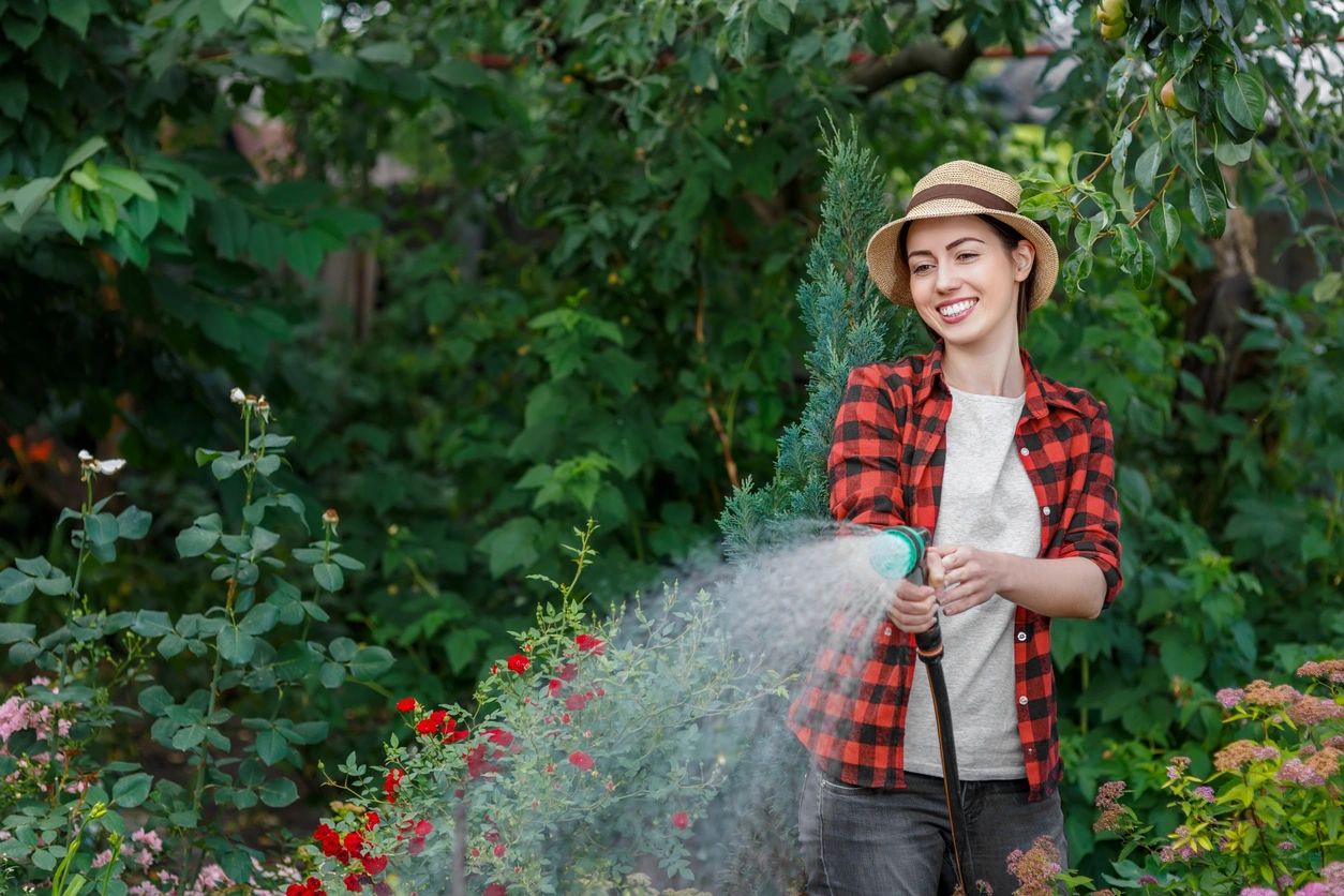 A woman Spraying water to plants