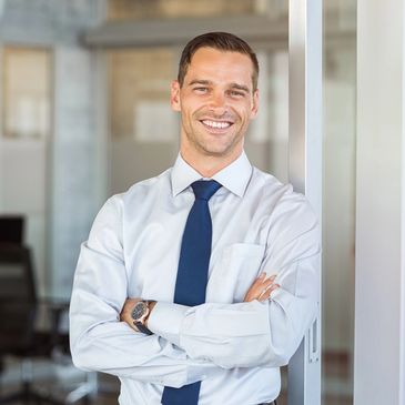 Confident businessman in white shirt and navy tie smiling at the camera.