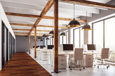 Modern office space with wooden beams and sleek workstations.