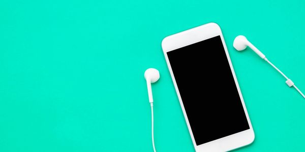 White smartphone with earbuds on turquoise background.