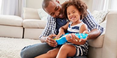 Man and daughter joyfully playing with her toy guitar.