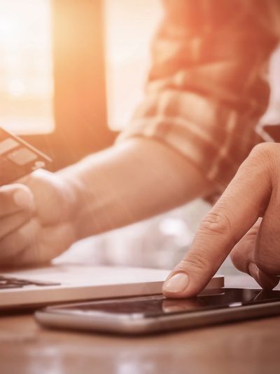Person using smartphone and holding a credit card for online payment.