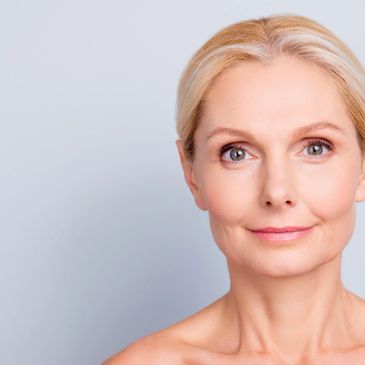 Smiling middle-aged woman with clear skin and blonde hair against a light background.
