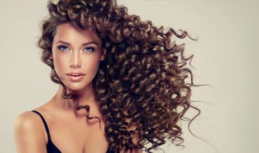 Woman with voluminous curly hair and glowing skin.