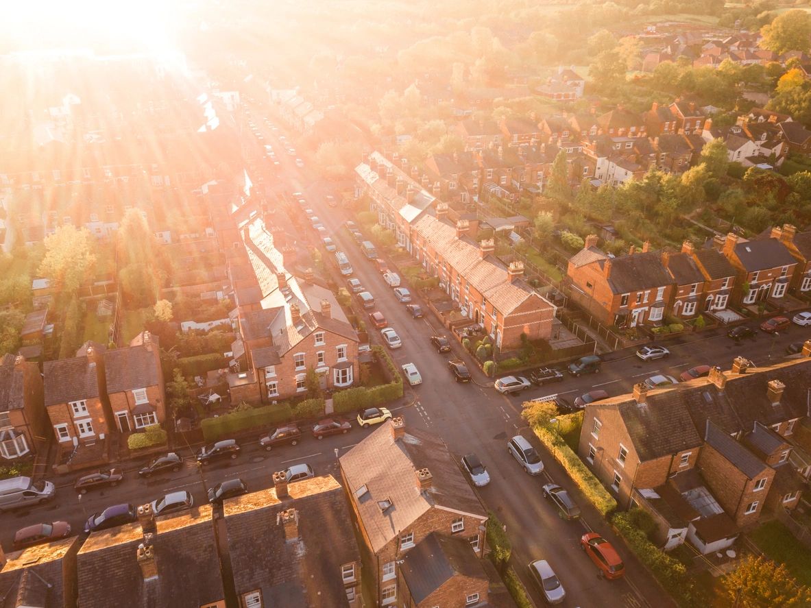 Top view of a city neighborhood overlooking the homes and parked cars in the intersection.