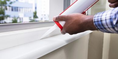 Person applying caulk to a window with a caulk gun