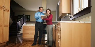 A woman looks at a tablet with a real estate agent to discuss renovations of the kitchen of her home