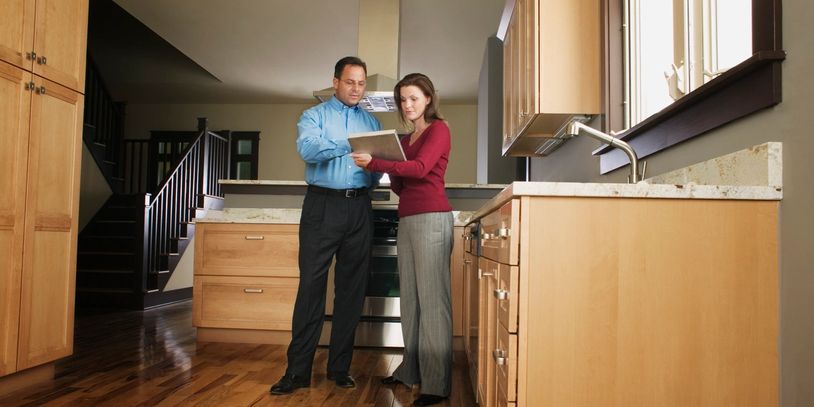A woman looks at a tablet with a real estate agent to discuss renovations of the kitchen of her home