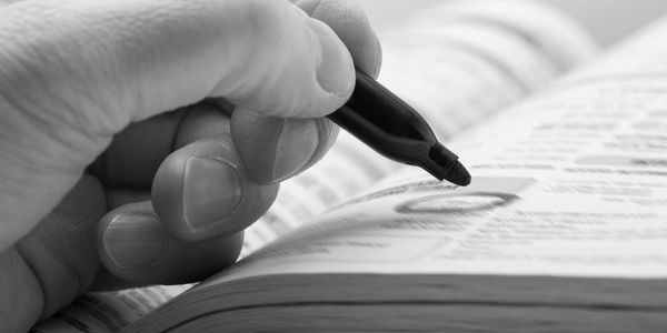 Hand circling text with marker in a book.