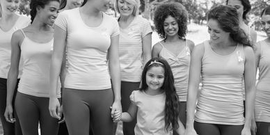 Women and a young girl walking together outdoors, smiling and holding hands.