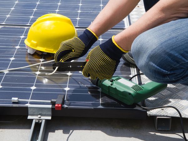 Worker cutting wires from a solar panel