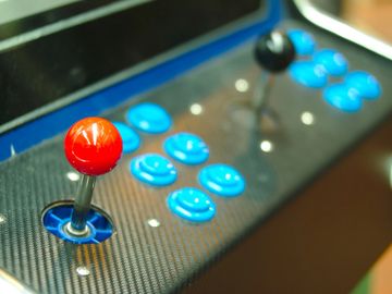 Close-up of arcade game joystick and buttons with vibrant red and blue colors.