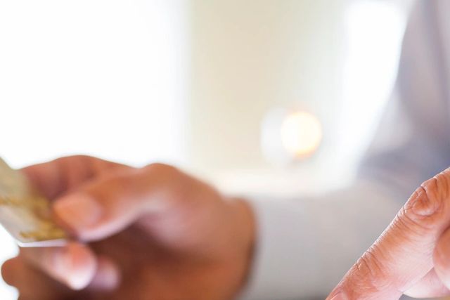 Person holding a credit card and using a smartphone.