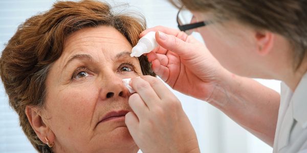 A physician placing eye drops into a patient's eye.