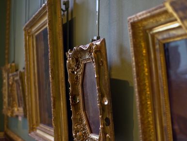 Close-up of ornate, antique picture frames hanging on a wall.