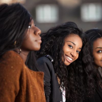 Three women with long hair, one smiling brightly at the camera.