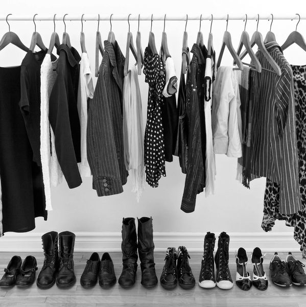 A monochrome wardrobe with black, white, and patterned clothes and matching shoes neatly arranged.