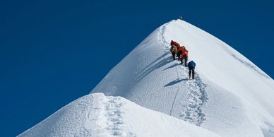 Grupo de personas subiendo a la cumbre de una montaña nevada