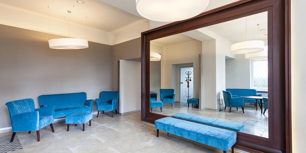 A modern room with blue velvet furniture and a large mirror.