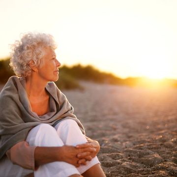 Woman sat on sand during sunset