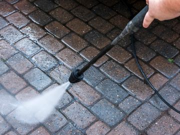 Pressure washing a stone patio with a high-pressure water spray.