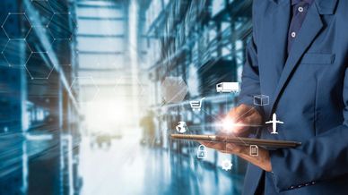 Businessman using a tablet with digital logistics icons in a warehouse.