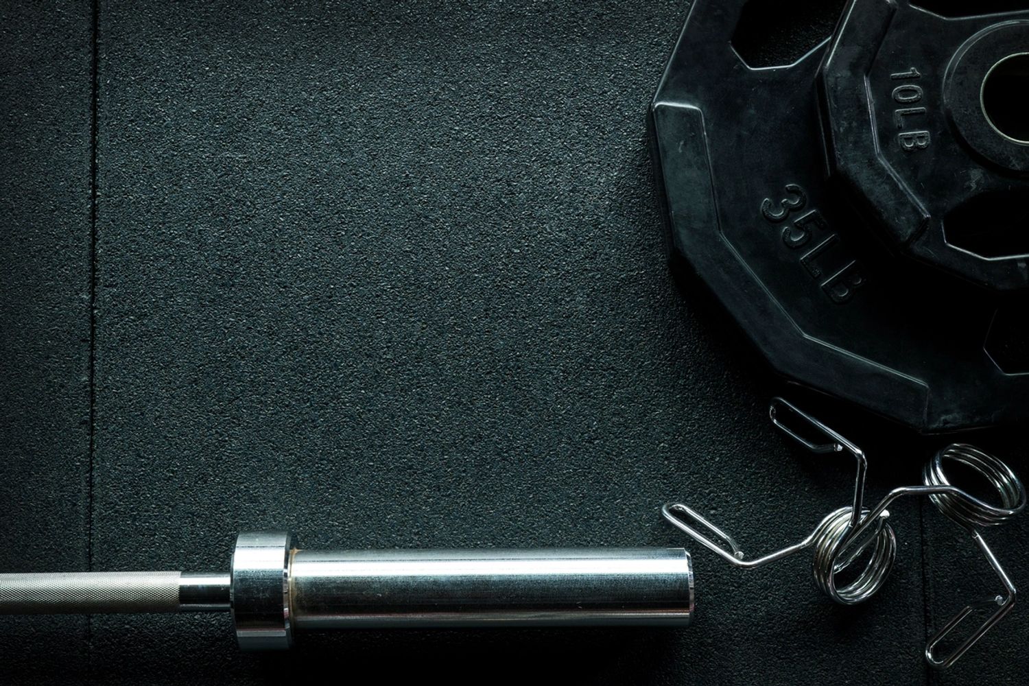 Barbell and weight plates on gym floor.