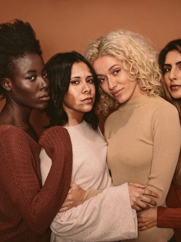 Four diverse women posing closely together.
