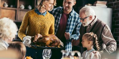 An older couple with a younger couple and 10-year-old girl gazing at Turkey on a platter.