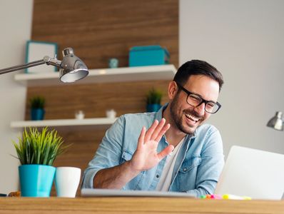 Teacher smiling and waving at a student on a computer screen.