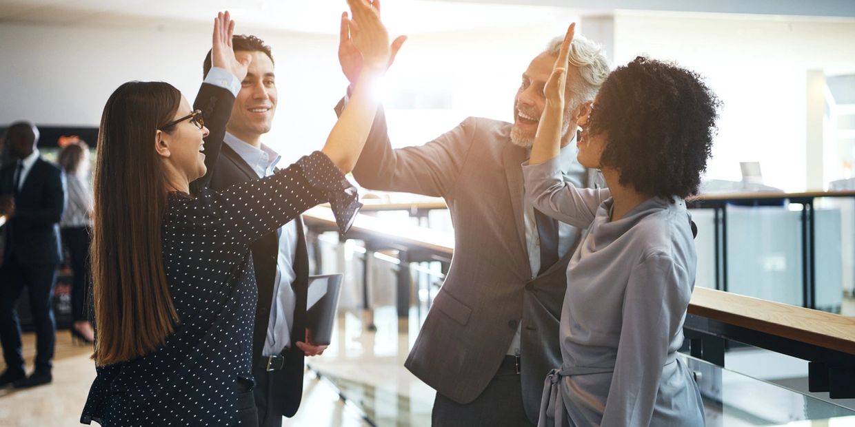 Four office professionals high fiving each other