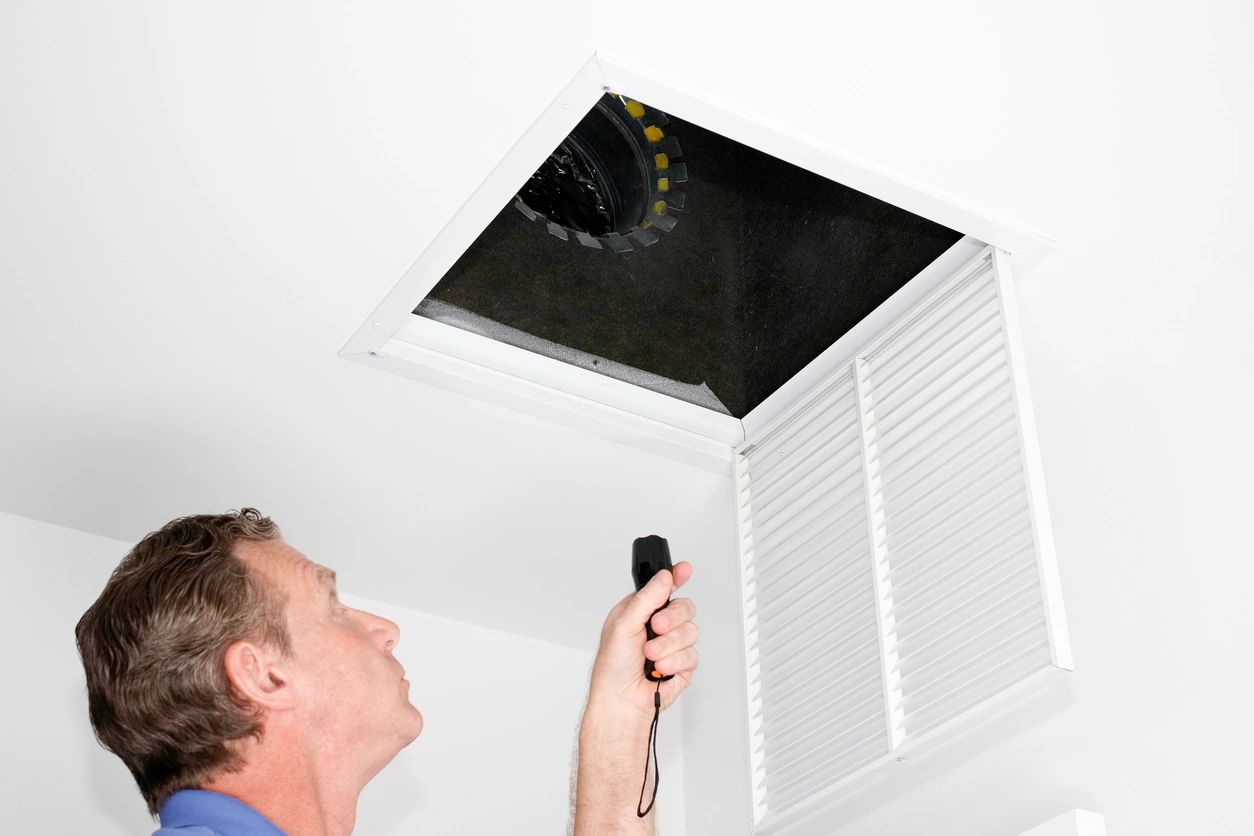 HVAC contractor looking up inside a return vent