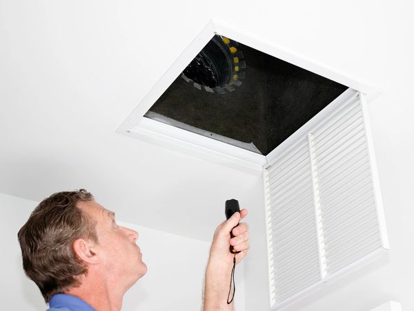 Man inspecting ceiling air vent duct.