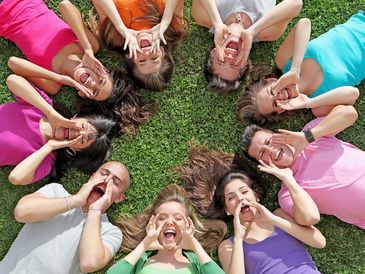a group of people laying on the grass in a circle.