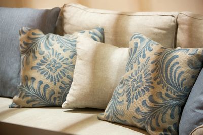 Decorative patterned and plain cushions on a beige sofa.