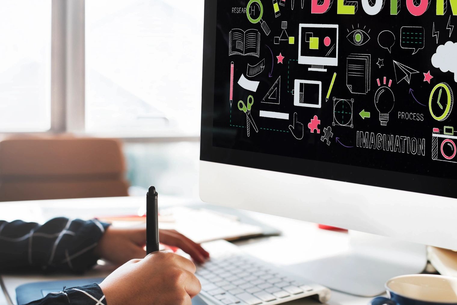 Person working on graphic design using a digital pen and computer.