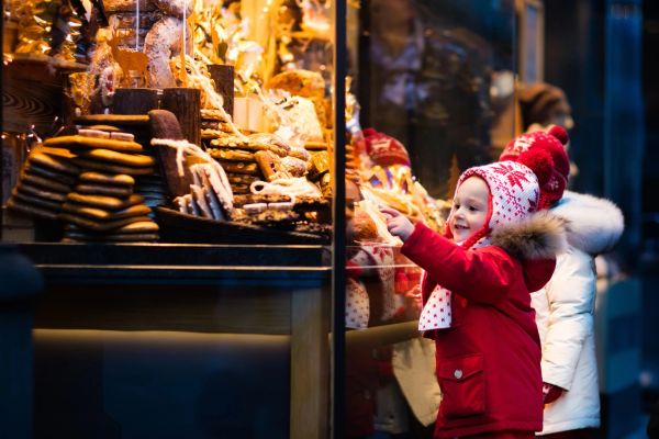 Child excitedly points at holiday treats in a shop window.