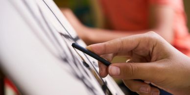 Mano dibujando con lápiz en papel.