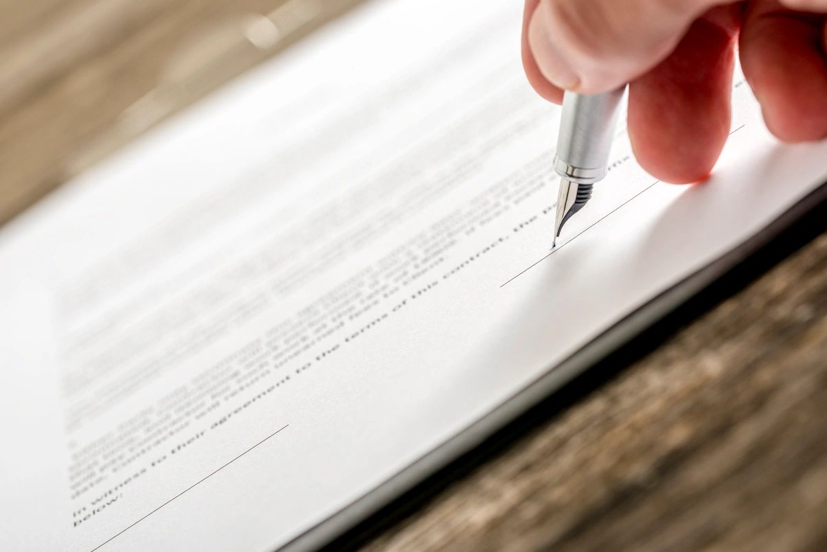 Close-up of a hand signing a document with a silver fountain pen.