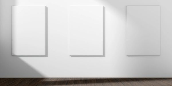 Three blank canvases hanging on a white gallery wall with wooden flooring.