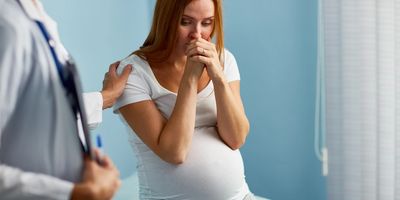 Pregnant woman sitting on table beside doctor