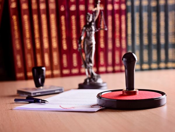 A small statue of Lady Liberty, a rectangular notary pad, documents, and a large circular stamp.